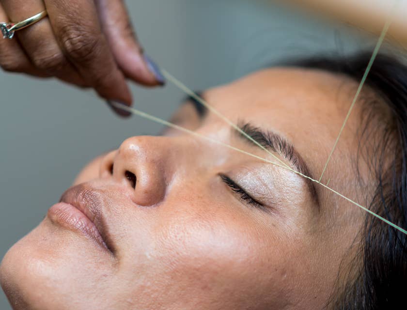 Woman having eyebrows shaped by threading service.