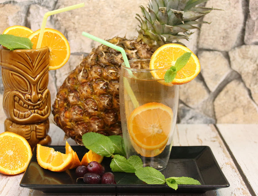 Une rangée de trois cocktails exotiques avec des fruits sur le rebord d'un tiki bar.