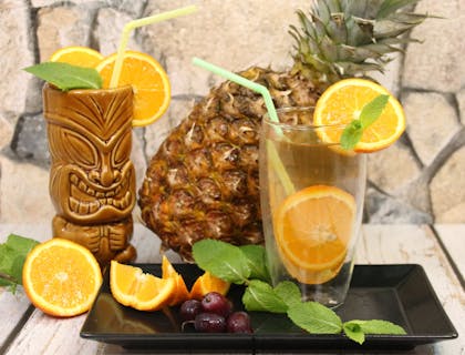 Tres bebidas frutales con alcohol en una superficie de madera en un bar tiki.