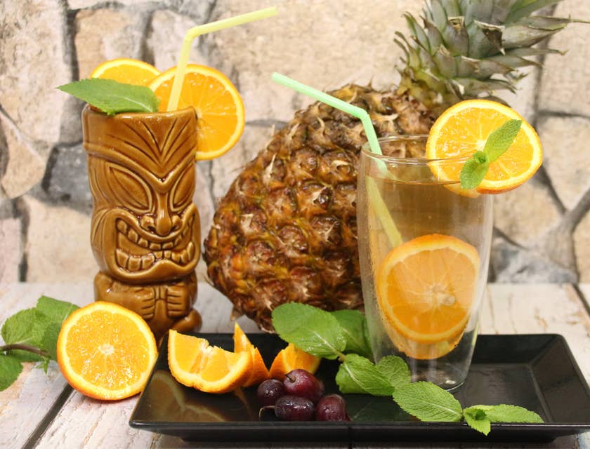 Una fila di cocktail tropicali con ananas sopra il bancone di un tiki bar.