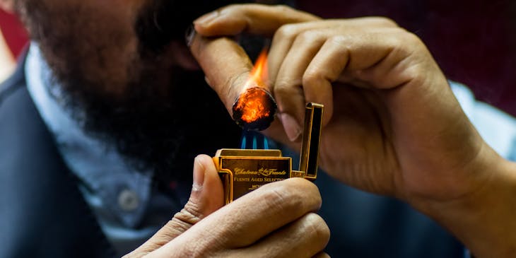A man lighting a cigar bought from a tobacco shop.