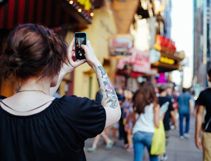 Una mujer caminando y tomándole foto a un lugar turístico en una empresa de tours..