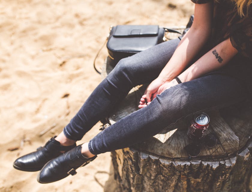 Una modella dal look trendy seduta sul tronco di un albero.