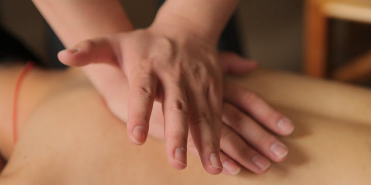 Tui na practitioner applying pressure to upper back of client.