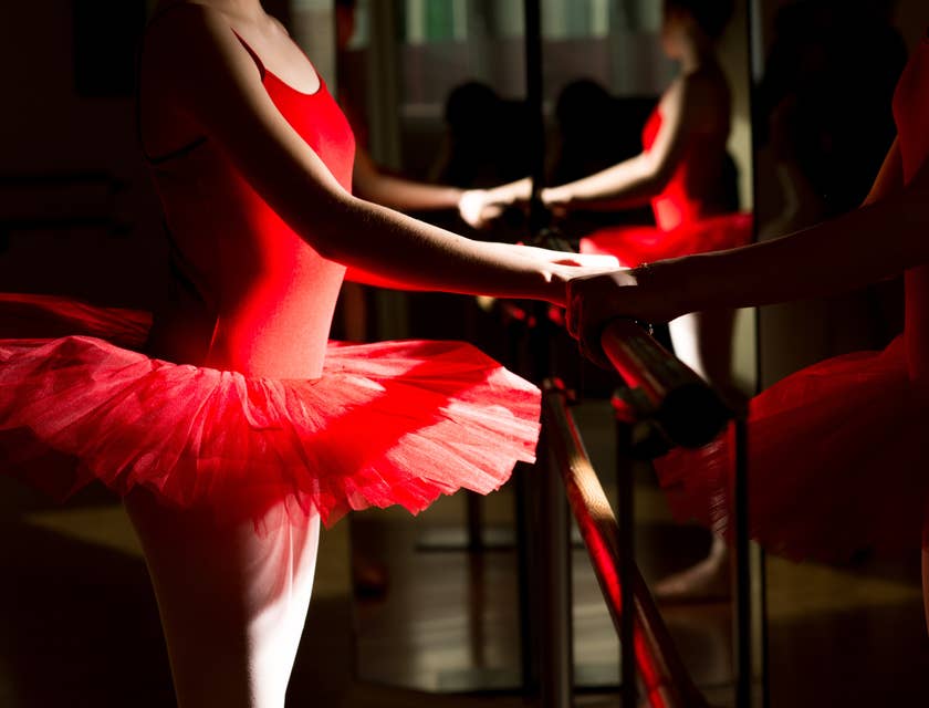 Una ballerina che indossa un tutù rosso - comprato in un negozio di tutù - e si guarda in uno specchio.