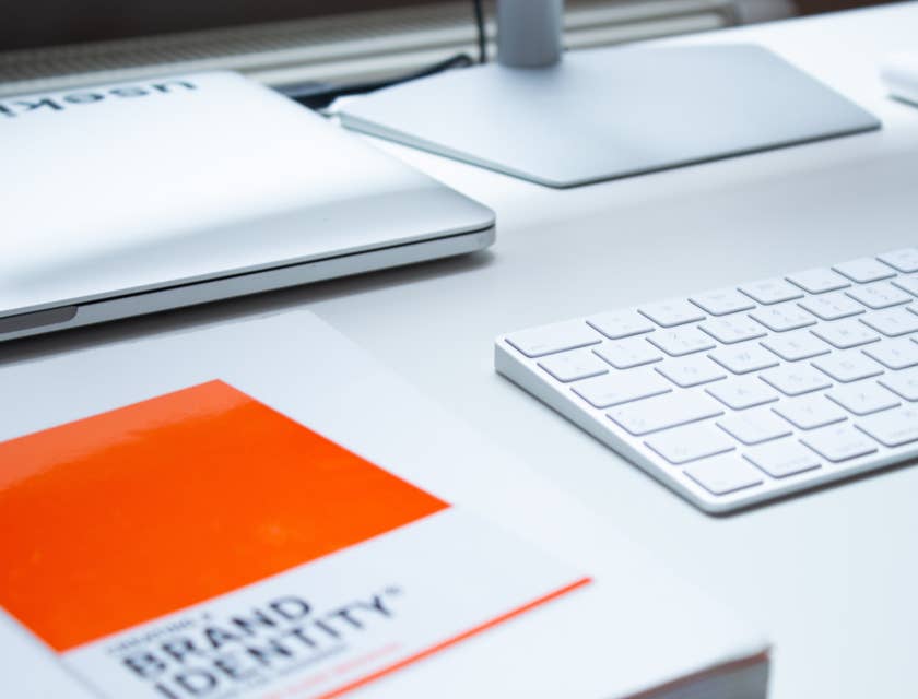 Un livre intitulé "brand identity" à côté d'un clavier et d'un écran d'ordinateur.