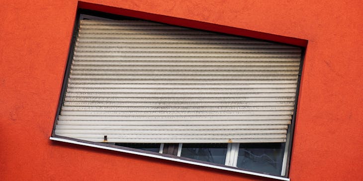 An unusual, tilted window frame in a red-orange wall.