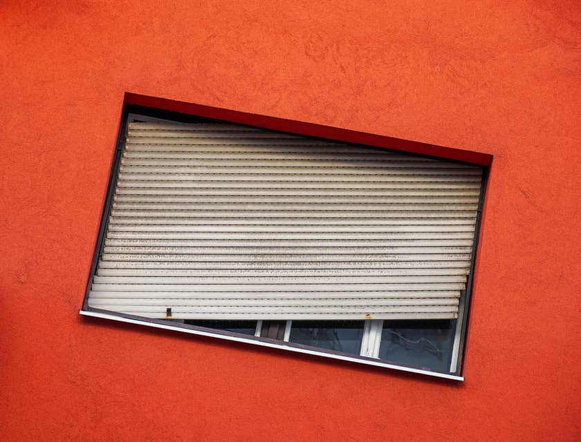 Un cadre de fenêtre inhabituel et incliné dans un mur rouge-orange.