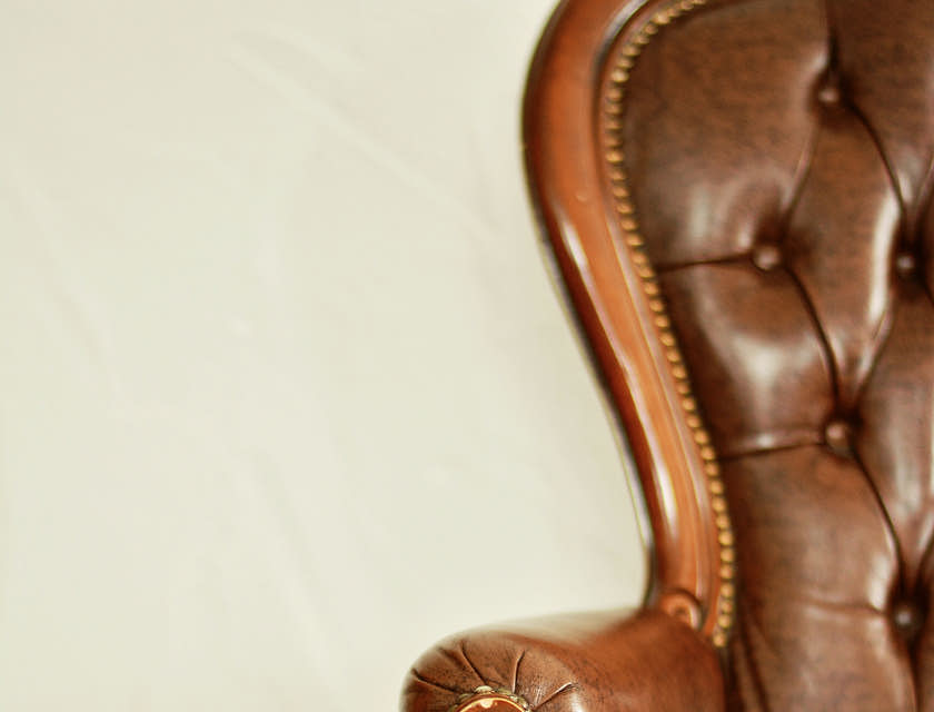 Fauteuil ancien avec revêtement en cuir marron.