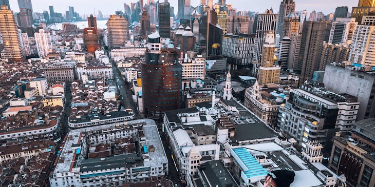 A person sitting on a rooftop overlooking an urban landscape.