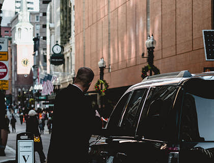 A valet standing next to a parked car.