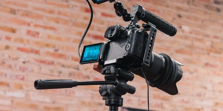 Video camera standing close to a brick wall.