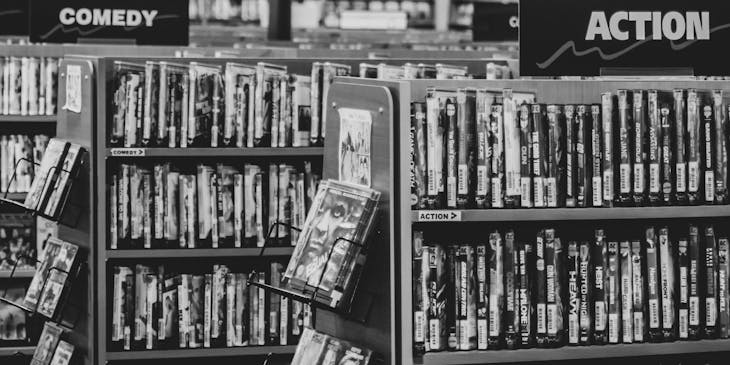 Black and white photo of a video rental store with videos on shelves.
