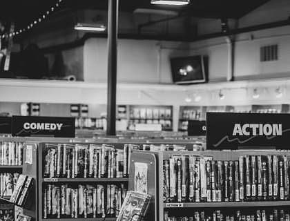 Une photo en noir et blanc d'un magasin de location de DVD et jeux vidéos avec des films et jeux sur des étagères.