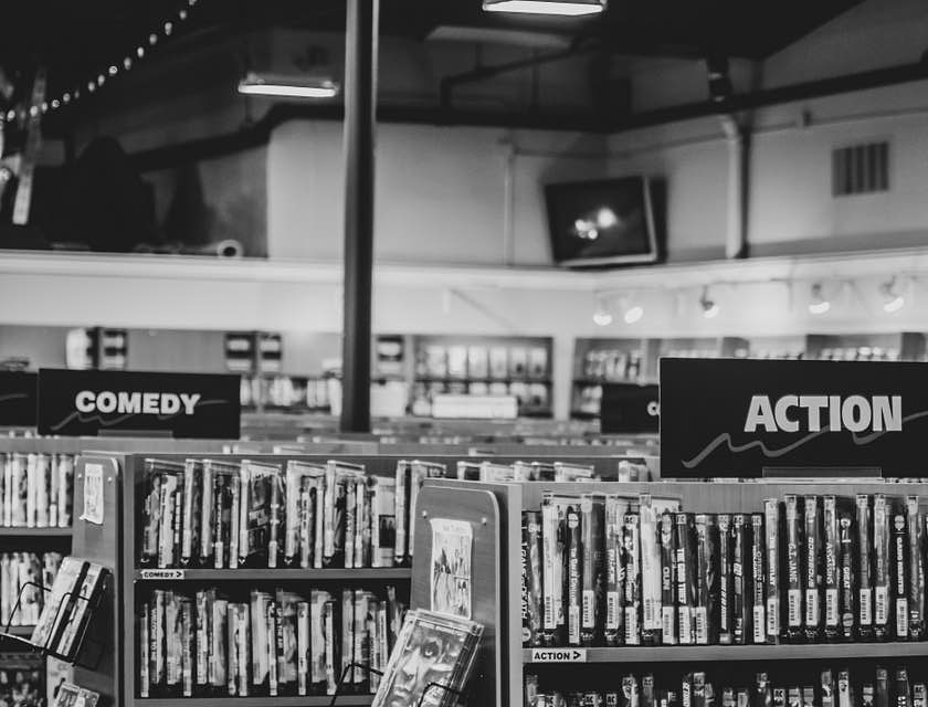 Une photo en noir et blanc d'un magasin de location de DVD et jeux vidéos avec des films et jeux sur des étagères.