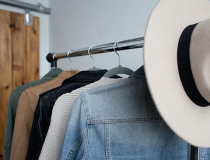 Una boutique vintage con un sombrero de vaquero sobre un aparador de chaquetas de mezclilla.