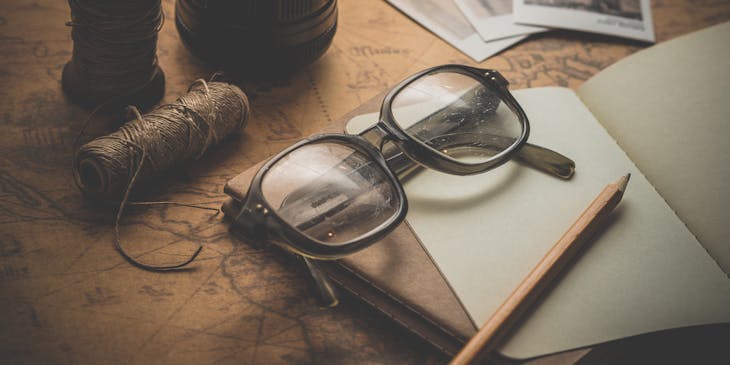 Vintage glasses, photos, notebook, and camera in sepia tone.