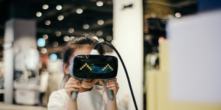 A young girl looking through virtual reality headset.