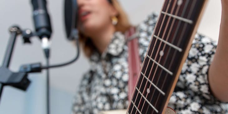 A vocal coach singing while playing guitar.