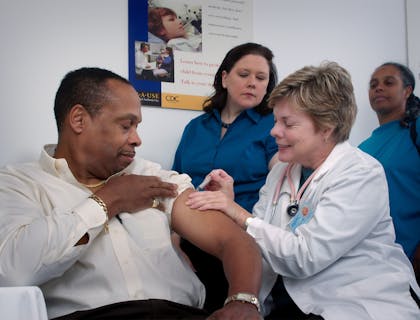 Woman injecting a man's arm at walk-in clinic.