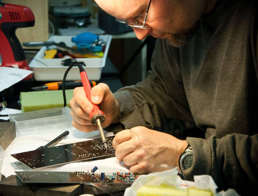 Homem consertando uma placa de circuito em uma empresa de aquecedores.