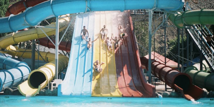 Children sliding down a water slide in a water park.