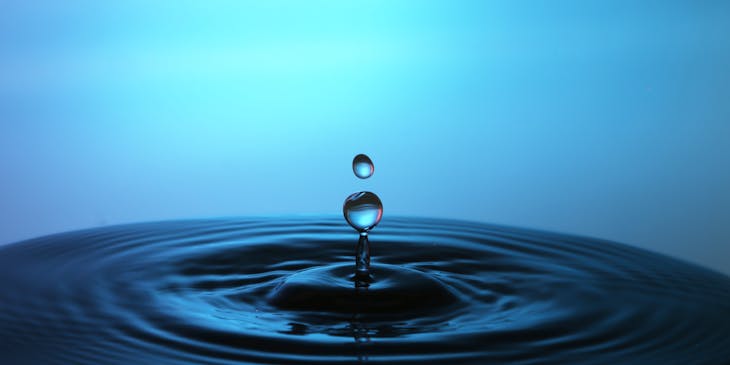 A close-up of water dripping into a body of purified water.