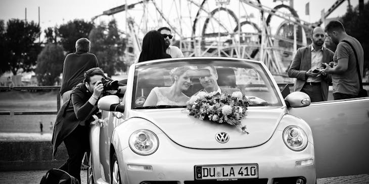Wedding photographer taking a picture of a couple in a car