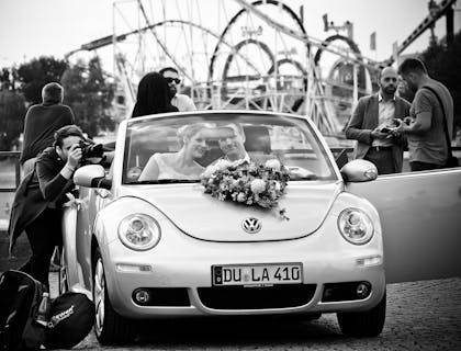 Fotógrafo de bodas tomando una foto de una pareja en un coche