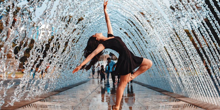 Ballerina dancing on glazed tiles under a water arch.