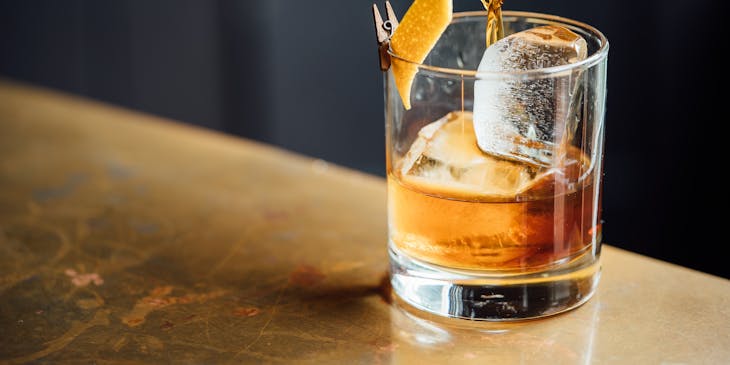 Close up of person pouring whiskey in a tumbler at a whiskey bar.