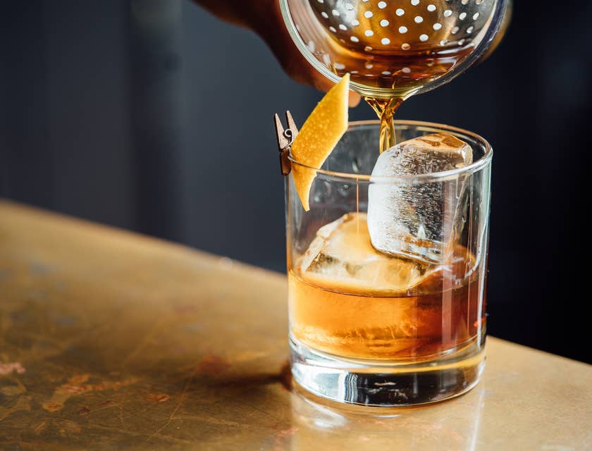 Un primo piano di una persona che versa whisky dentro ad un tumbler in un whisky bar.