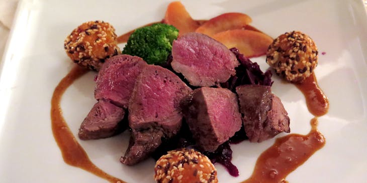 Venison dish on a white ceramic plate in a wild game restaurant.