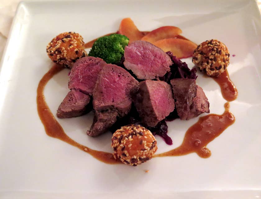 Venison dish on a white ceramic plate in a wild game restaurant.