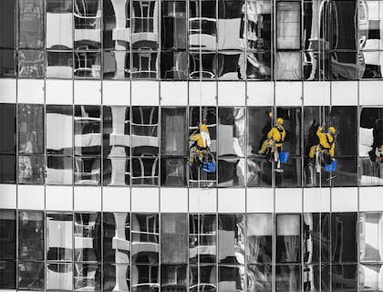 Hombres limpiando vidrios en el exterior de un edificio de un negocio de limpieza de ventanas.