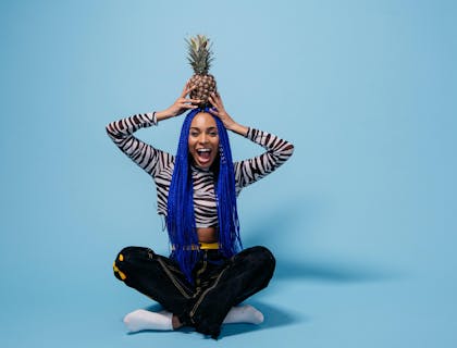 A healthy woman smiling and holding a pineapple.