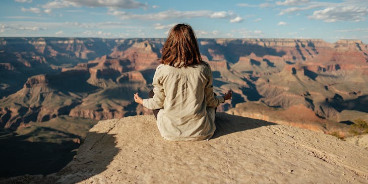 Woman meditating on rocky landscape.