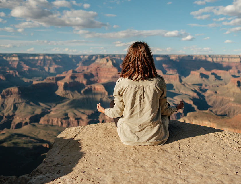 Un femme méditant devant un paysage rocheux.