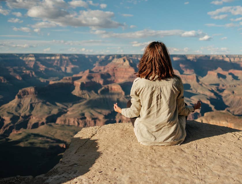 Un femme méditant devant un paysage rocheux.