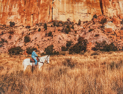 A man riding a horse near the mountains in New Mexico.