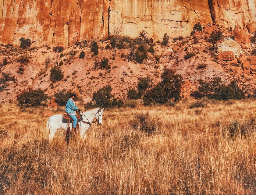 A man riding a horse near the mountains in New Mexico.