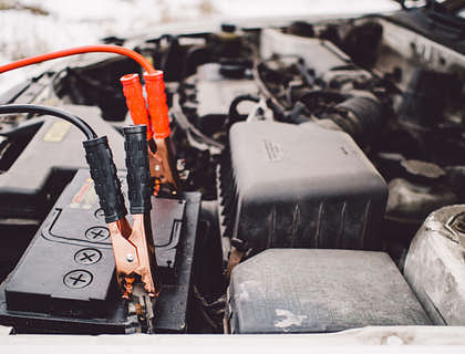 Due cavi per la batteria attaccati a una batteria per auto in un'officina di un elettrauto.
