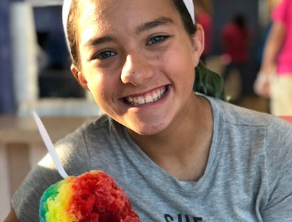 Una niña sonriendo y sosteniendo una minuta hondureña de tres sabores.