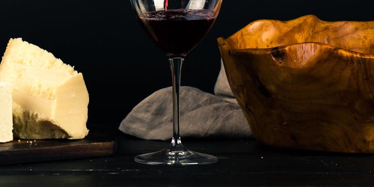A glass of red wine being poured in a wine bar.