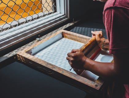 Un uomo che sta serigrafando una stampa vicino a una finestra di una serigrafia