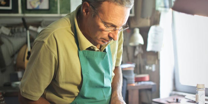Um homem consertando um violino em uma empresa de reparos.