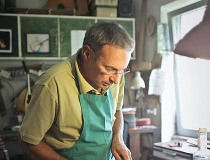Um homem consertando um violino em uma empresa de reparos.